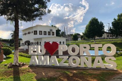 Placa 'Eu Amo Porto Amazonas' com edifício ao fundo.