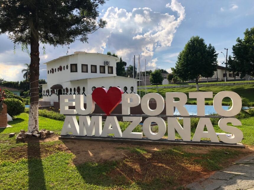 Placa 'Eu Amo Porto Amazonas' com edifício ao fundo.