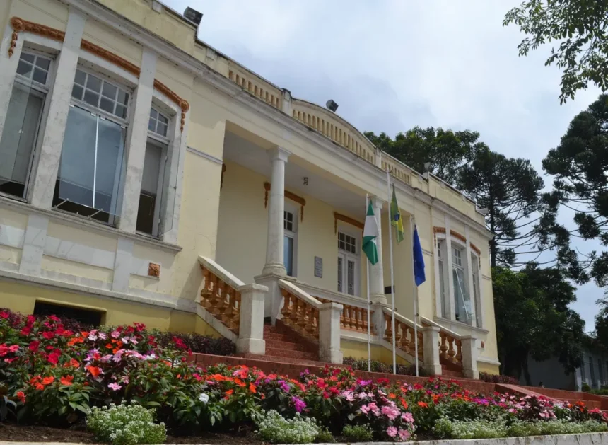 Prédio histórico com jardim e bandeiras na fachada.